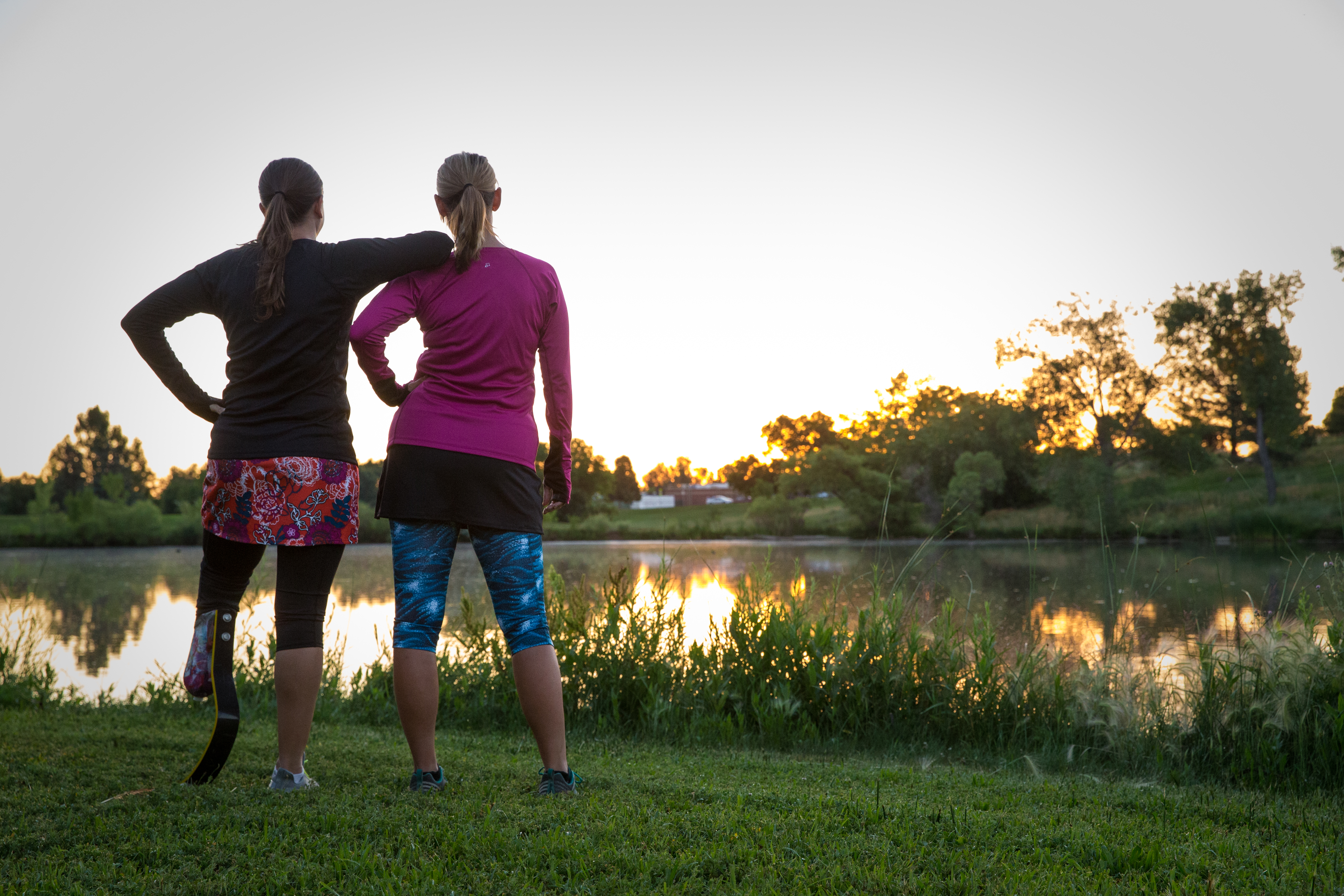 me and my friend Jenn in running gear watching the sunrise over the lake with our backs to the camera