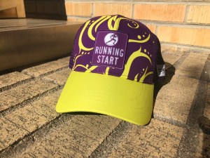 Purple & yellow trucker hat with Running Start logo on bricks