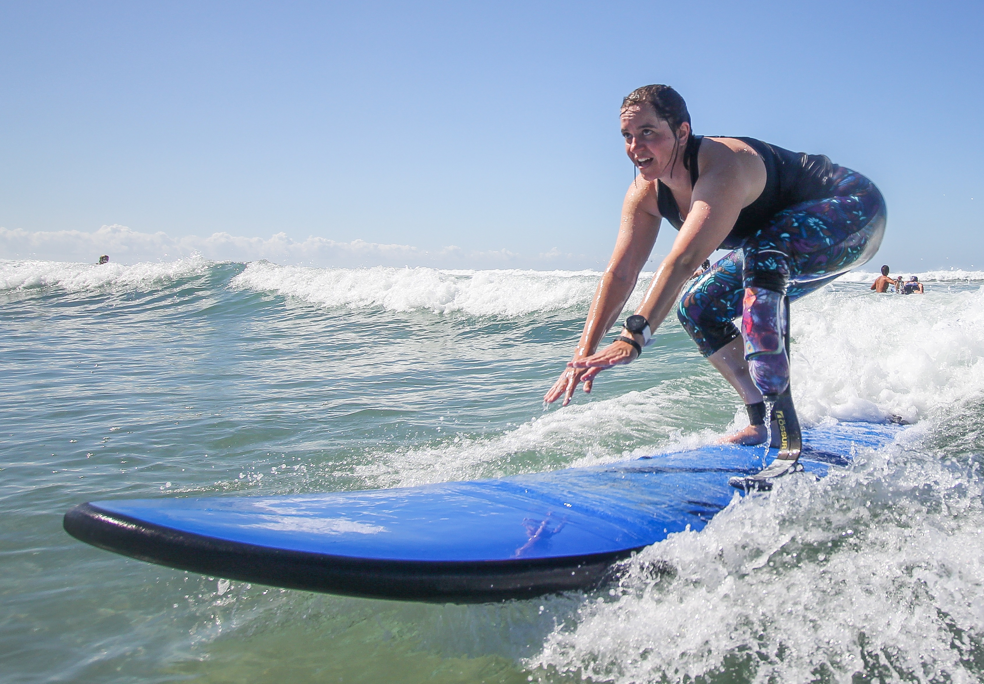 Emily standing on a blue surfboard