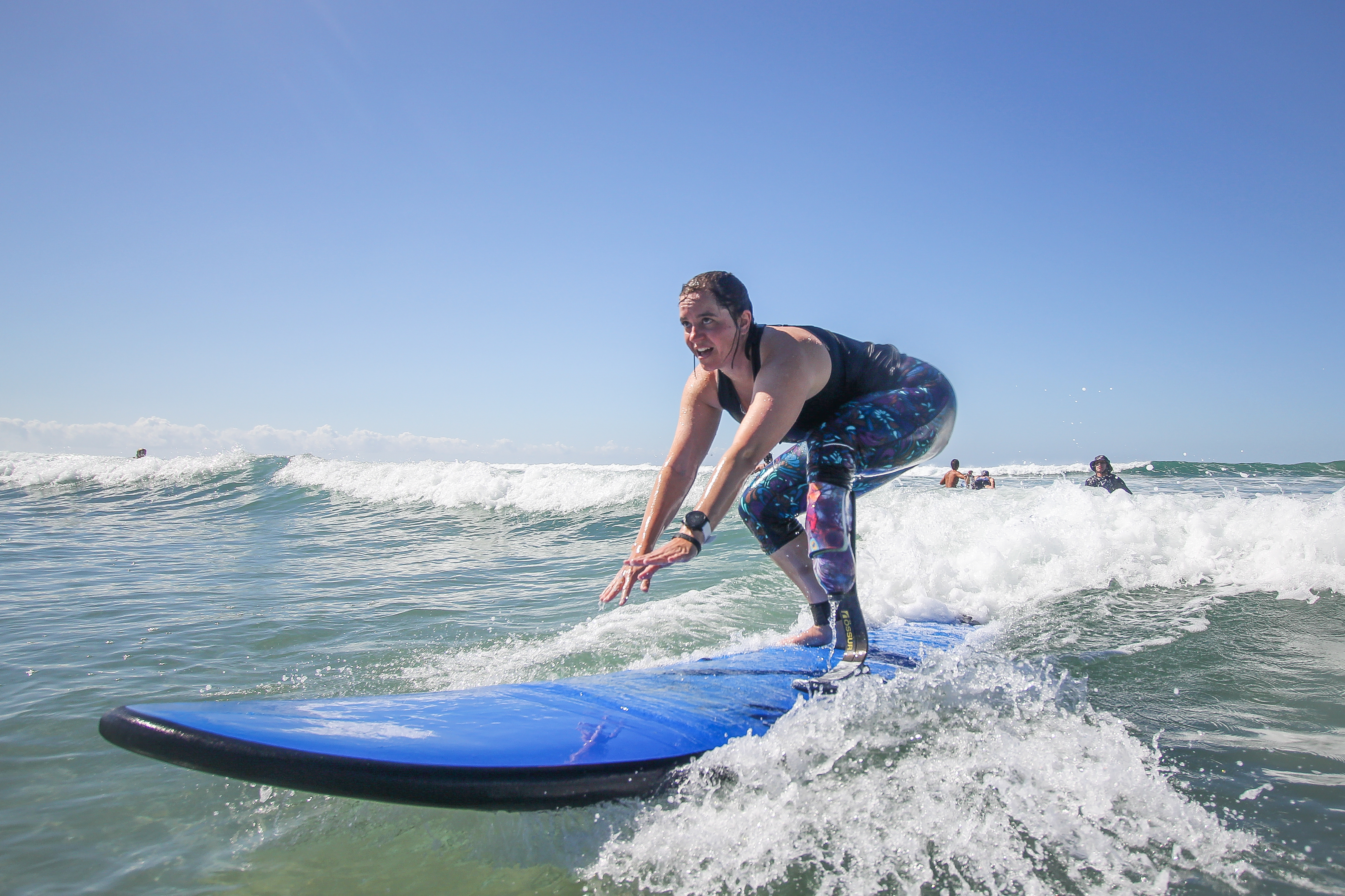 Emily standing up on a surfboard, looking towards the beach