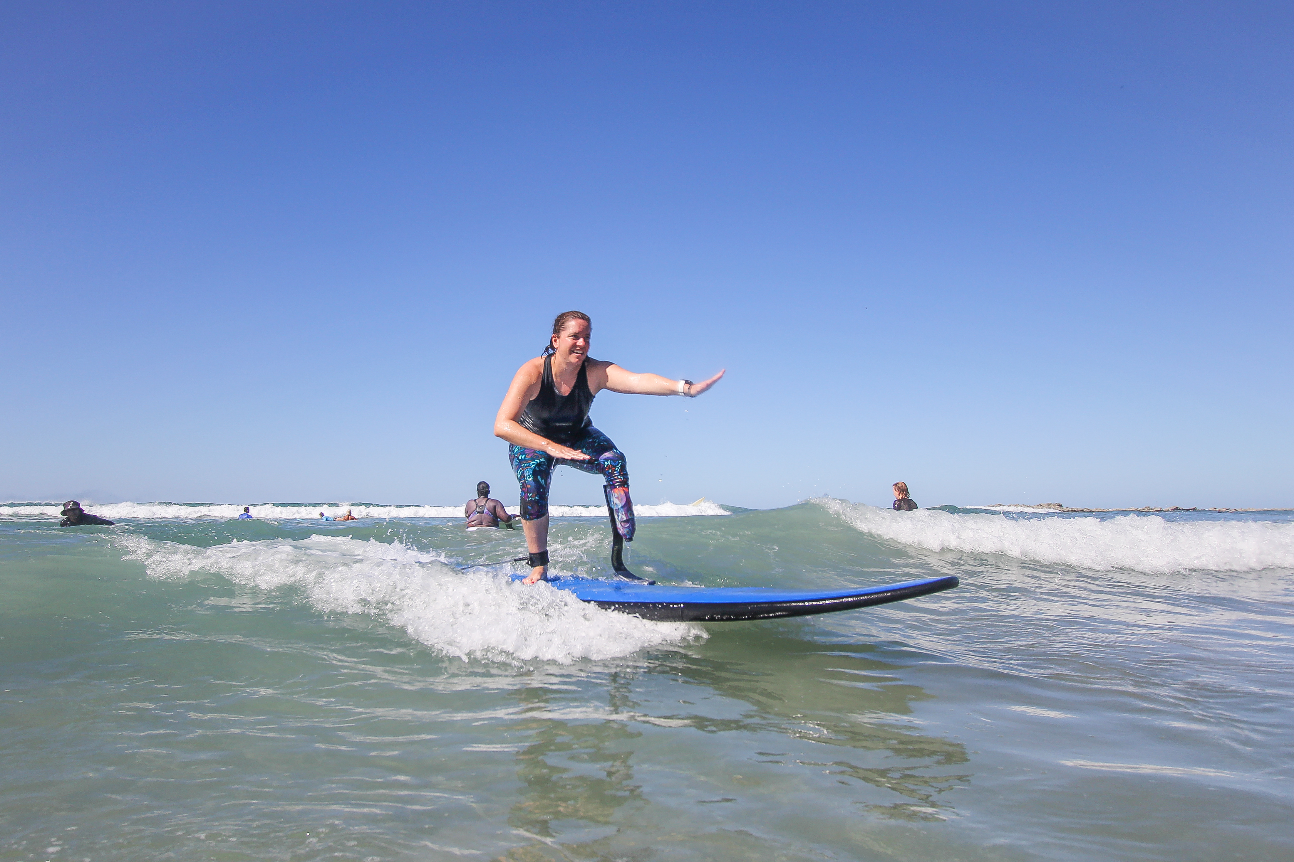 Emily standing up on a blue surfboard